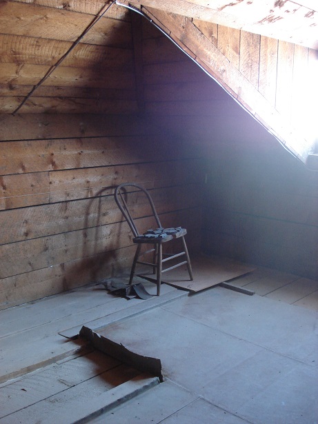 A lonely chair sits in the corner of the attic.